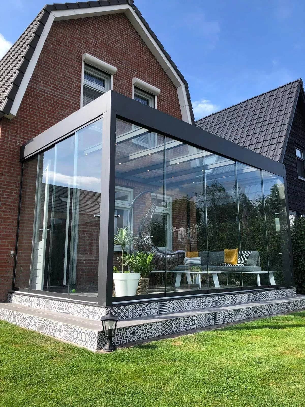 Glas-Schiebeanlage als Windschutz an der Terrasse eines Klinkerhauses