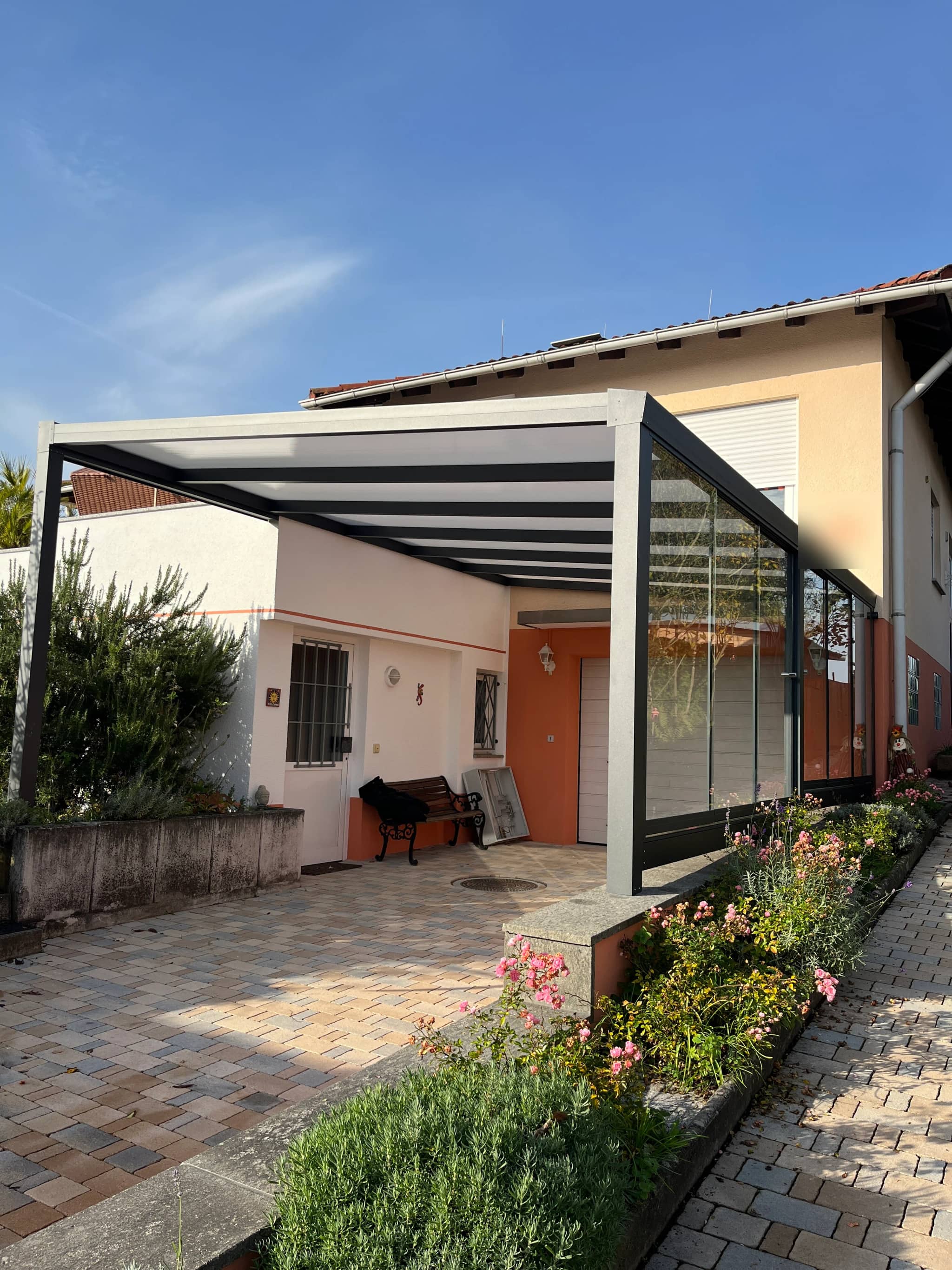 Carport aus Aluminium mit geschlossener Seite vor dem Eingang eines Wohnhauses