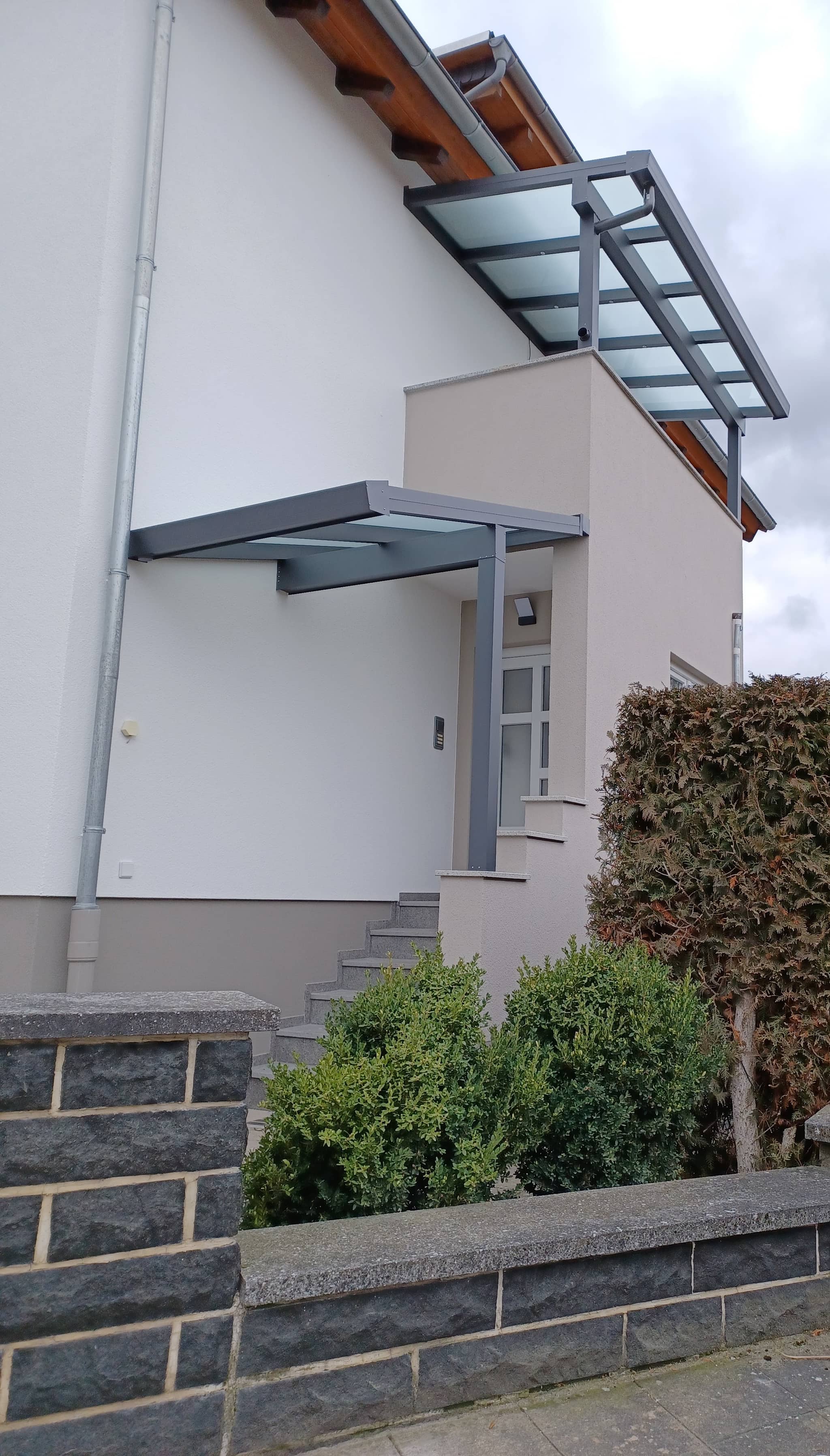 Eingangsüberdachung aus Aluminium in Anthrazit mit lichtdurchlässigem Glasdach über dem Hauseingang, Referenzprojekt von Beckel Überdachungen