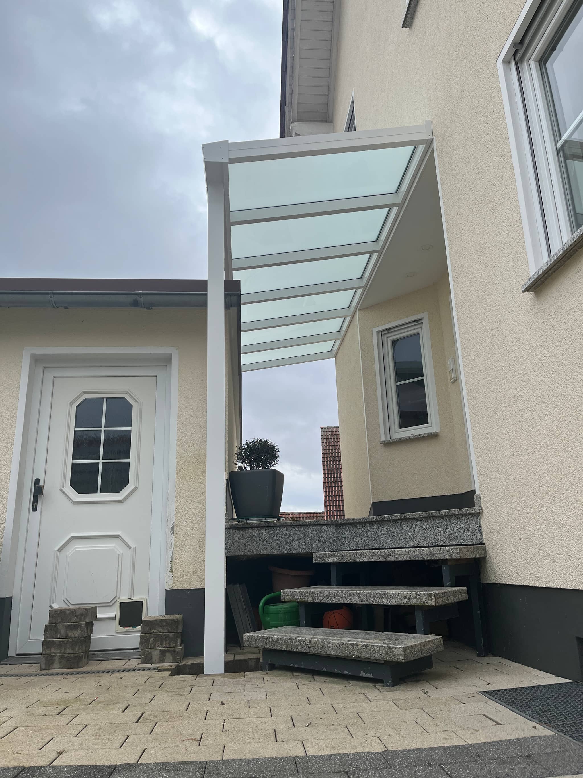 Eingangsüberdachung aus Aluminium mit lichtdurchlässigem Dach über einer Außentreppe zur Haustür