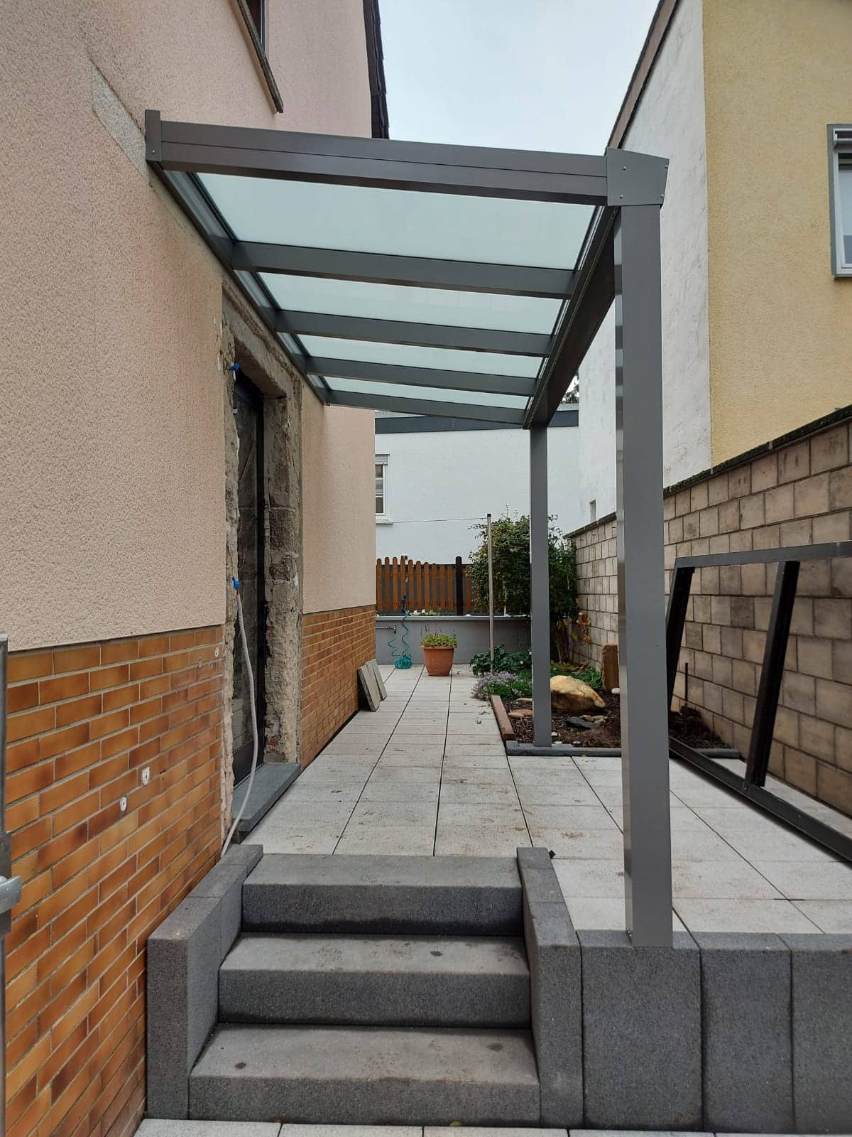 Eingangsüberdachung aus Aluminium mit lichtdurchlässigem Dach über den Stufen zum Hauseingang