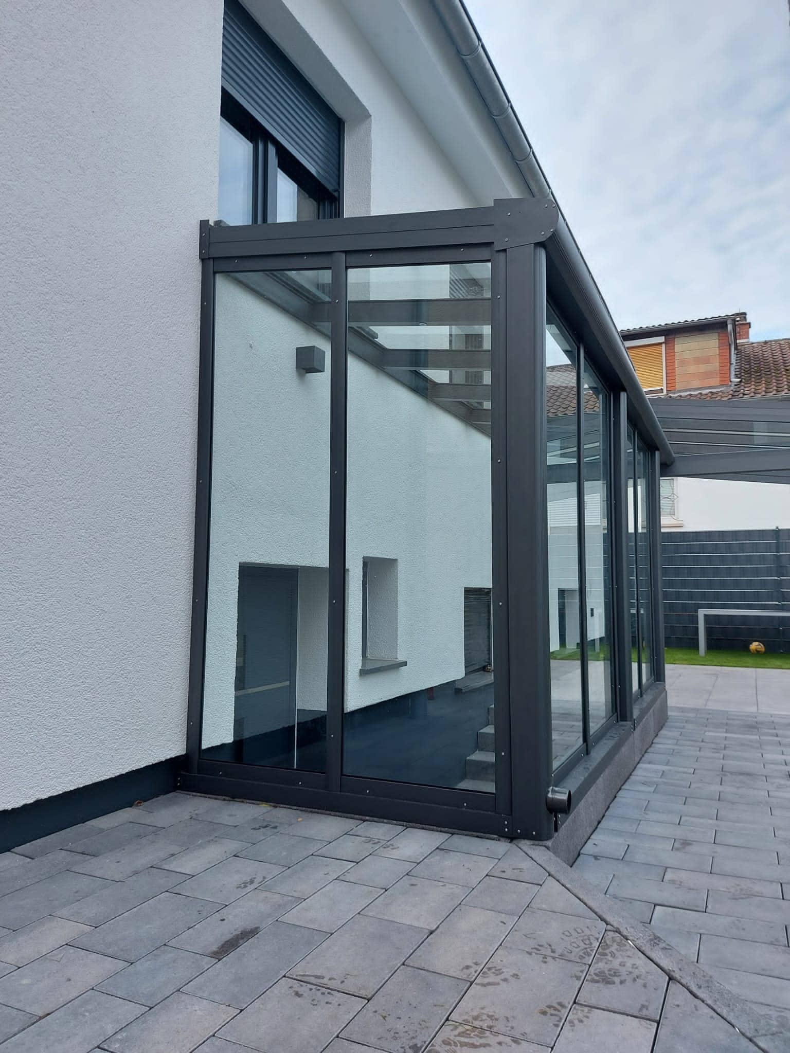 Eingangsüberdachung aus Aluminium in Anthrazit mit seitlichen Glaswänden vor dem Hauseingang