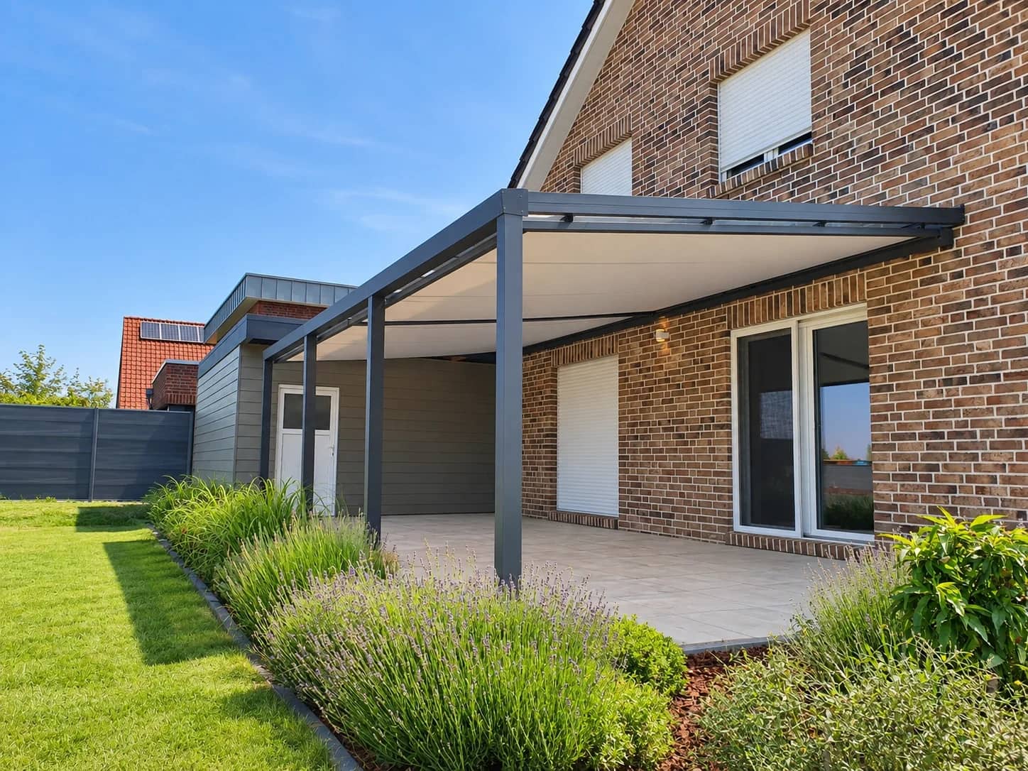 Terrassenüberdachung aus Aluminium in Anthrazit mit geschlossener Dacheindeckung an Klinkerhaus über gefliester Terrasse