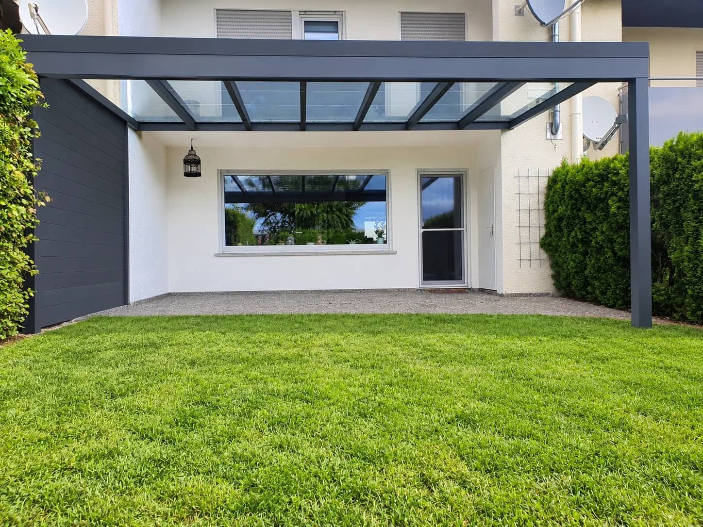 Terrassenüberdachung aus Aluminium in Anthrazit: Pultdach mit klarer Eindeckung über gepflegtem Rasen