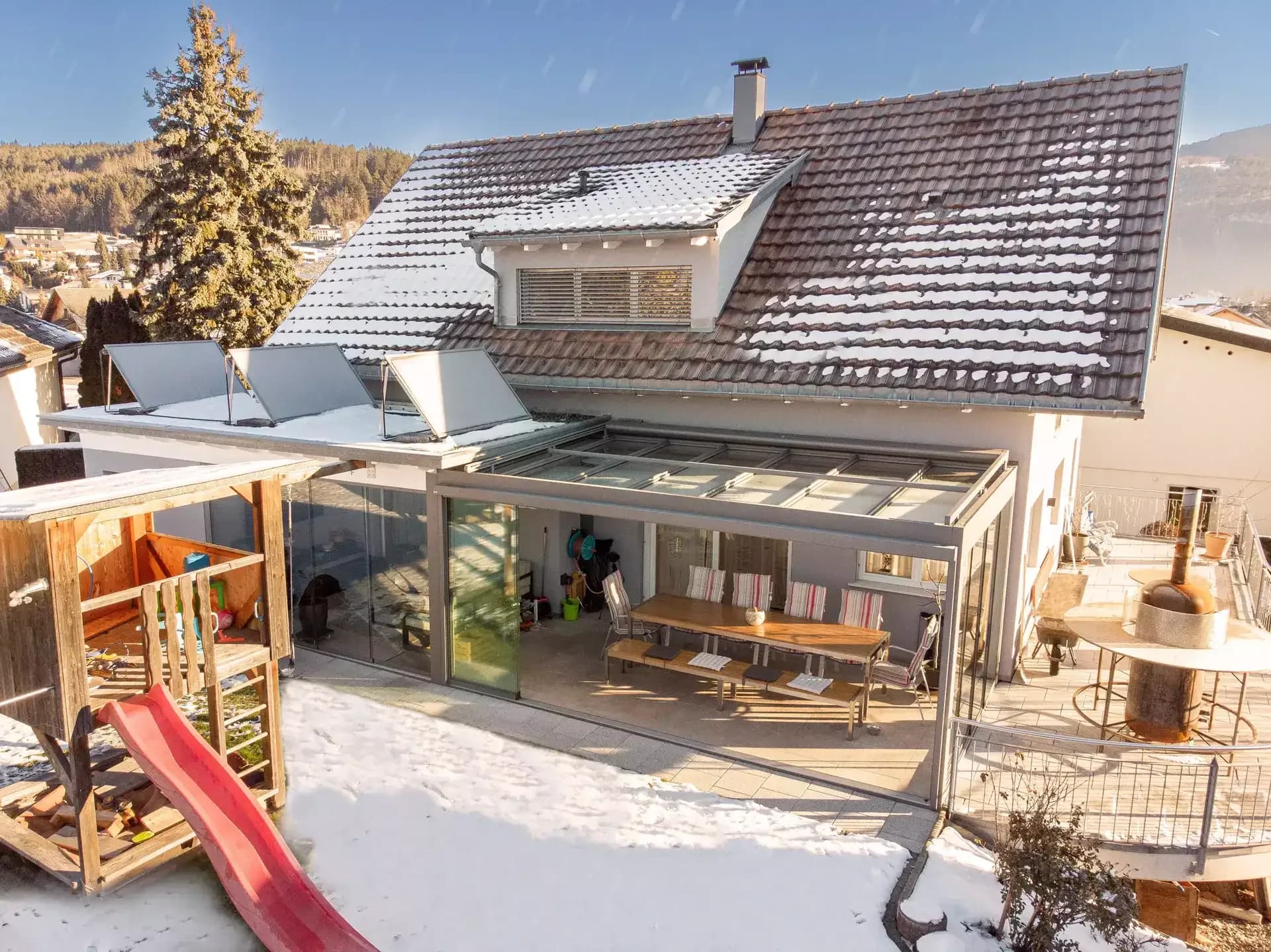 Flachdach-Überdachung aus Aluminium über einer Holzterrasse mit Esstisch und Stühlen