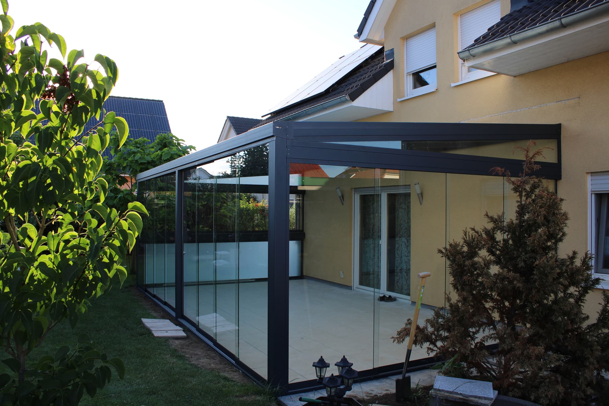 Sommergarten mit anthrazitfarbenem Aluminiumgestell und umlaufenden Glaselementen an einem Einfamilienhaus in Hessen